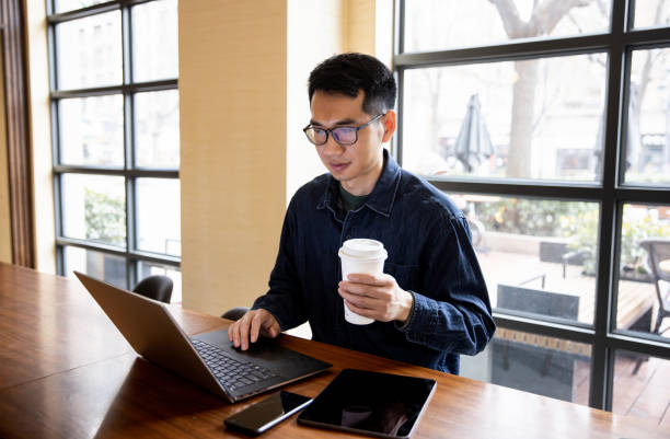 istock Man working and holding a cup of coffee at cafe 1369247672