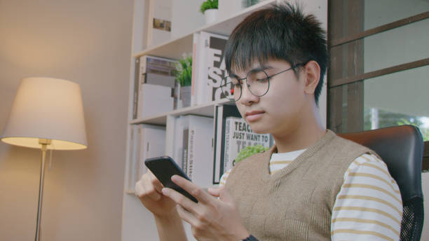 istock Young man holding and using smartphone in living room. 1369251846