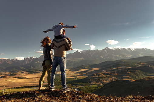 Happy family of mother father and young son walks in mountains. Active weekend travel concept