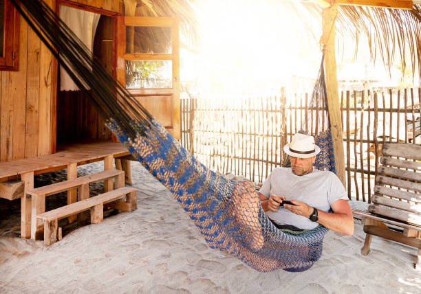 man with hat uses smartphone remotely at the beach, near cabin. Playa La Ventanilla