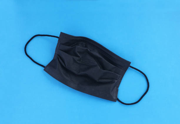 istock Black mask for corona protection isolated on blue background 1369259383