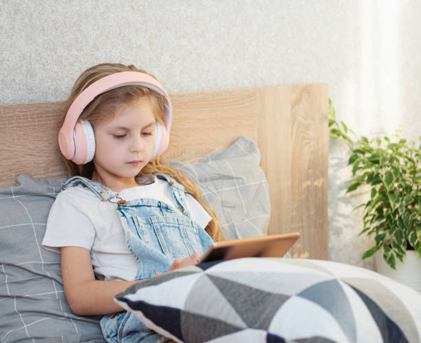 istock Cute Little girl  using tablet at home 1369260836