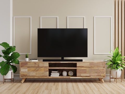TV en gabinete con pared de color crema y piso de madera. photo