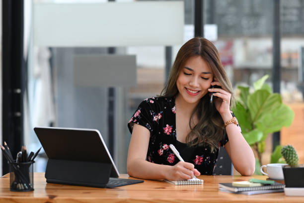 istock Happy businesswoman using computer tablet and talking on mobile phone with business partner. 1369262989