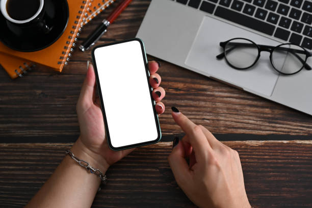istock Above view young woman using smart phone on wooden desk. 1369264597