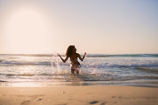Woman in bikini inside the water of the sea in the beach at sunset. Selective focus.