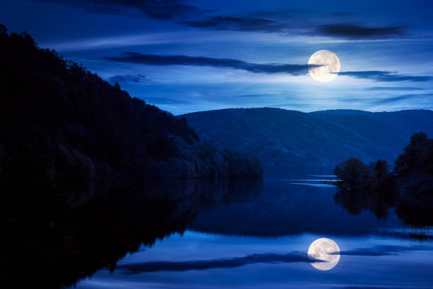 beautiful scenery with lake at night. dark clouds reflecting on the water surface. wonderful autumnal landscape in mountains in full moon light
