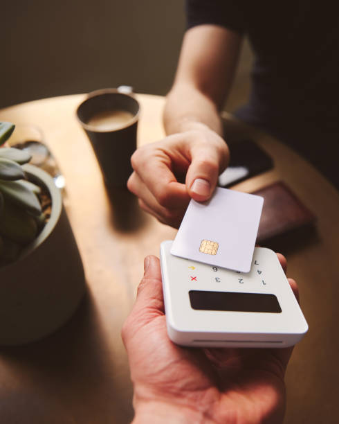 コーヒーを支払う非接触カードリーダーのクレジットカードを手でタップする - credit card reader ストックフォトと画像