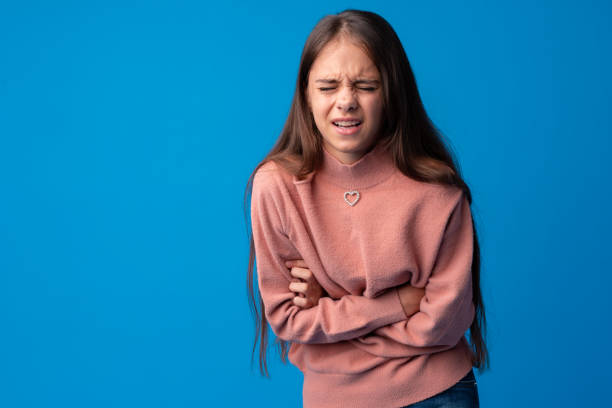 istock Young girl with bellyache isolated on a blue background 1369269485