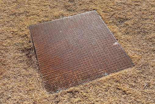 Close-up of rusty iron lid on a winter lawn.