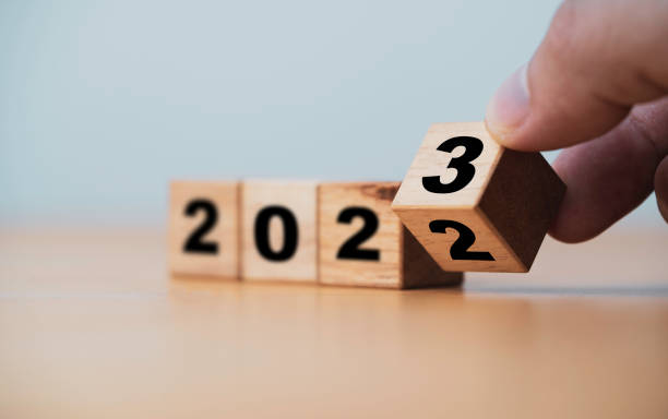 cubo di blocchi di legno che si capovolge tra il 2022 e il 2023 per il cambiamento e la preparazione buon natale e felice anno nuovo. - il giorno di anno nuovo foto e immagini stock