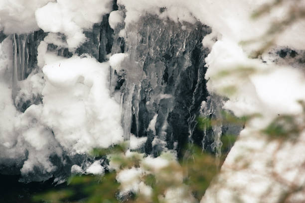 A close-up shot of intricate icicle formations and frozen water droplets creating a captivating winter texture. The scene emphasizes the artistic and natural beauty of ice in a frozen environment.