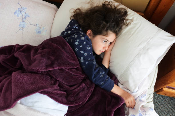 istock Sad young girl lying in bed 1369272004