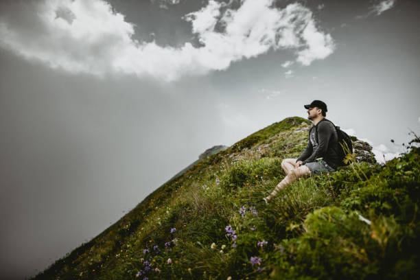 istock Tourist sitting on the grass in the mountains 1369272117