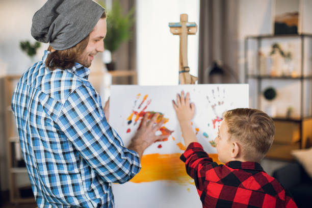小さな息子がキャンバスに描く教える父 - artists canvas indoors childhood small ストックフォトと画像