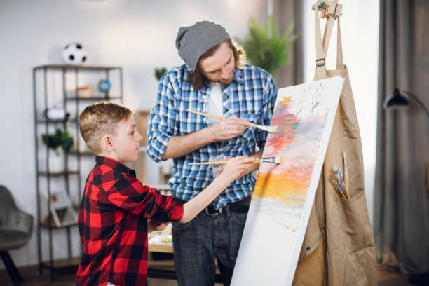 istock Father and son drawing together on easel at home 1369272232