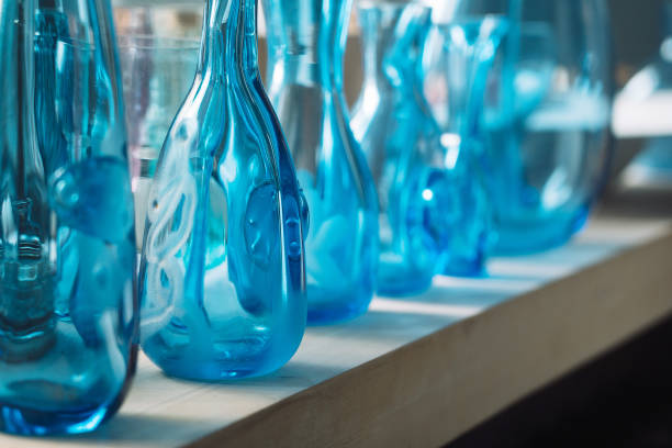 bottles of different sizes and shapes in blue on a shelf.