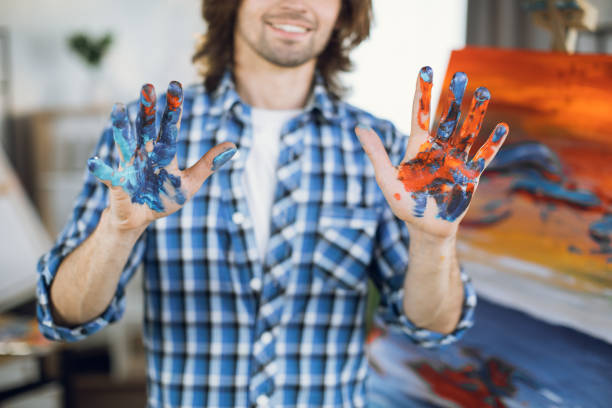 istock Artist showing his hands covered with paints after drawing 1369275052