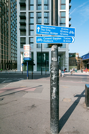 A sign showing the direction to several places in London outside Waterloo Station in Lambeth, London. People and the Tube symbol can be seen in the background.