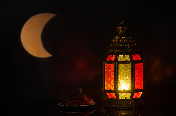istock Lantern and small plate of dates fruit with moon shape from light on background 1369277570