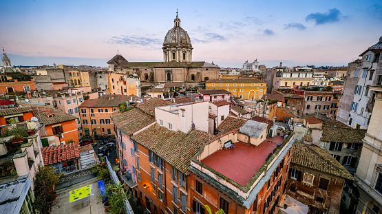 A suggestive cityscape on the roofs of Rome and the Campo de Fiori district, in the core of the Eternal City, with the baroque dome of Sant'Andrea della Valle church at center. The Campo de Fiori district is an area of the Eternal City much loved and visited by tourists and residents for the presence of ancient churches and noble palaces and for the countless artistic and cultural treasures of the Renaissance and Baroque era. But Campo de Fiori is also famous for the characteristic flower, fruit and vegetable market that occupies the square every day and for the presence of numerous trendy restaurants and pubs. Around the square, in the ancient Parione and Regola districts, you can explore dozens of characteristic alleys, where you can discover the essence and soul of Roman life. In 1980 the historic center of Rome was declared a World Heritage Site by Unesco. Super wide angle image in high definition and 16:9 format.