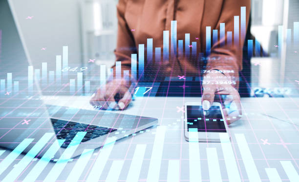 istock Businesswoman or stock trader analyzing stock graph chart using smartphone with touchscreen and laptop to buy or sell stock, forex bar charts, internet trading concept 1369280894