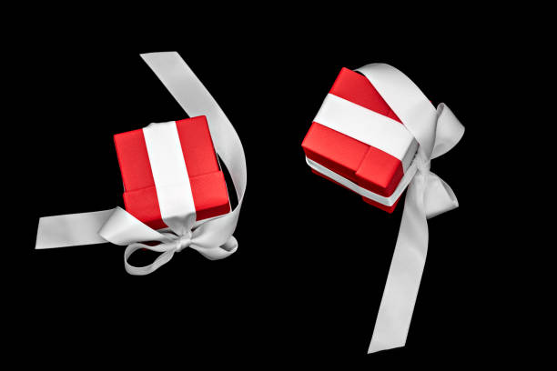 Two red gift boxes with white bows levitate isolated on black background. Place for text, copyspace.