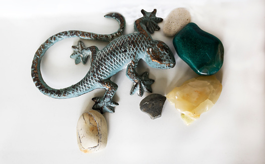 On a white background, precious stones and a decorative lizard made of stone