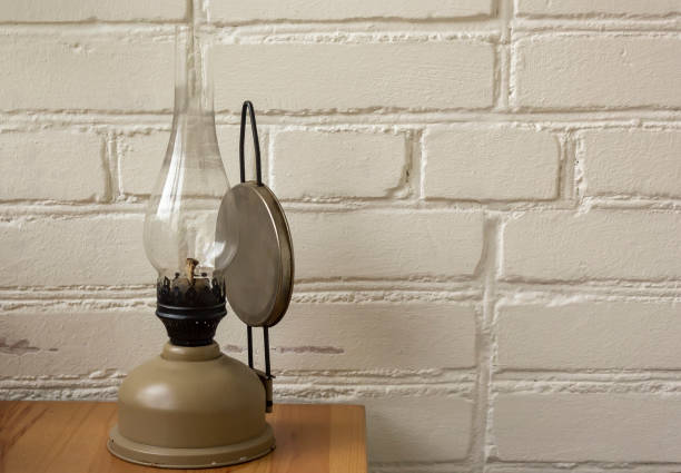 istock An old kerosene lamp standing on a wooden table against a white brick wall. 1369285307