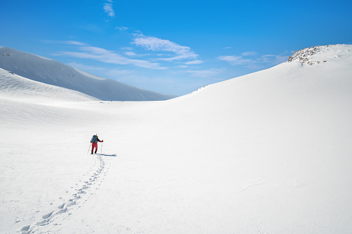 Alpinist climber is walking on mountain with harsh snowy conditions