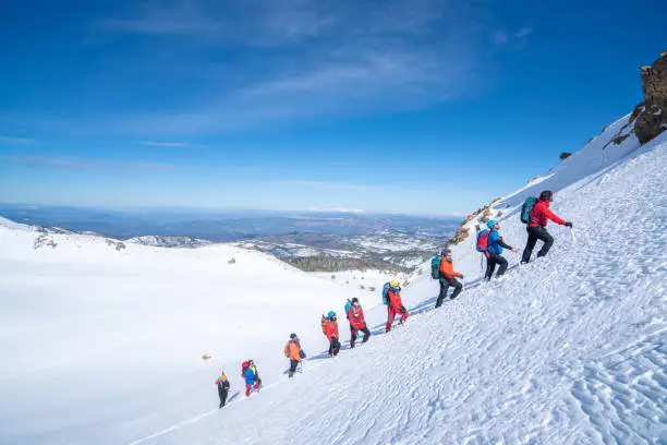 Photo of Mountain alpine climbing team is walking in a row in high altitude mountain peak in winter