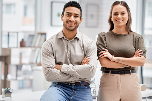 Cropped portrait of two young businesspeople standing with their arms folded in the office
