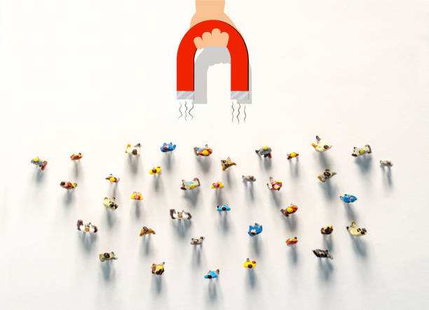 Personnel recruitment and a magnet attracts good employee leaders. 
Lead magnet with hand attracts figures of people on a white background. Concept of Attracting of customers, sales and online traffic stock photo