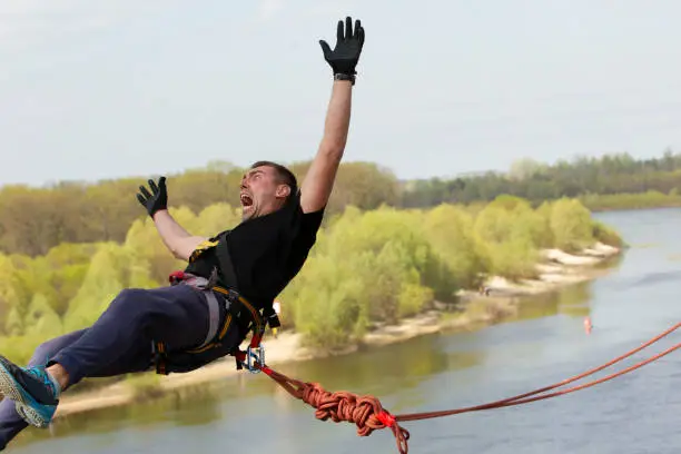 A man makes an extreme jump from a bridge on a rope.