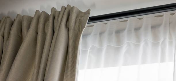 double layer day and night curtains on black rod in living room stock photo