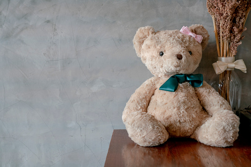 brown toy teddy bear sitting on wooden table background with gray copy space