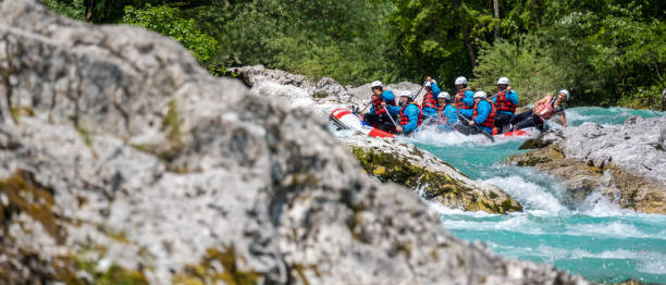 People adjusting balance in raft during riding in rocky section of track People adjusting balance in raft during riding in rocky section of track. Turquoise water between limestone stones. Rafting in wild mountain Soca river, Slovenia. primorska stock pictures, royalty-free photos & images