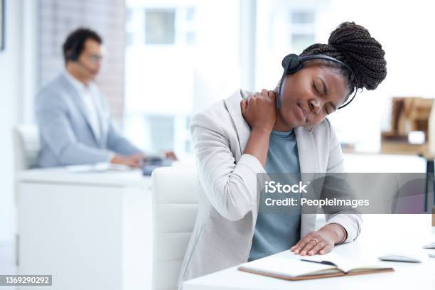 Shot Of A Young Call Centre Agent Experiencing Neck Pain While Working In An Office Stock Photo - Download Image Now