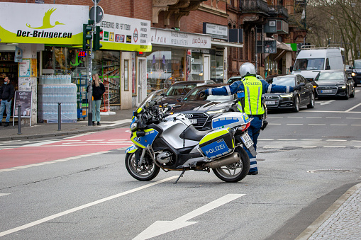 Wiesbaden, Germany - February 05, 2022: German motorbike officer safeguarding an accident scene on a busy junction in the center of Wiesbaden, Germany