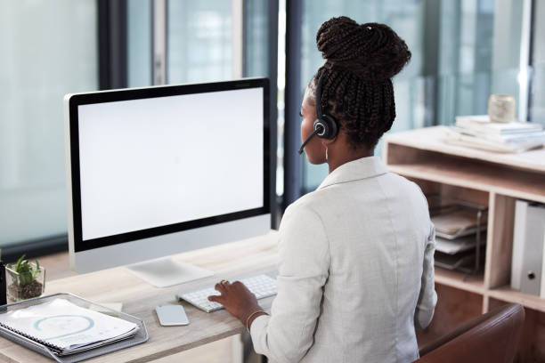 rearview shot of a young call centre agent working on a computer in an office - african descent customer service representative computer service imagens e fotografias de stock