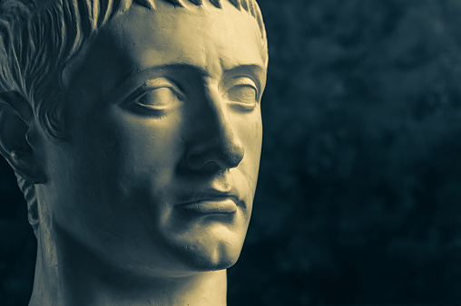 Bronze color gypsum copy of ancient statue of Germanicus Julius Caesar head for artists on dark textured background. Renaissance epoch. Plaster sculpture of man face. Template for art design