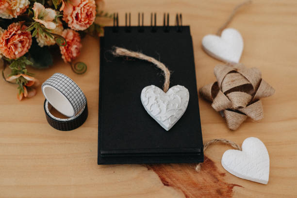 istock notebook with black sheets with copy space, bouquet of flowers and a white heart. 1369294286