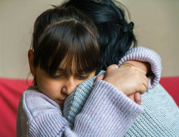 Worried young foster mother comforting embracing adopted child stock photo