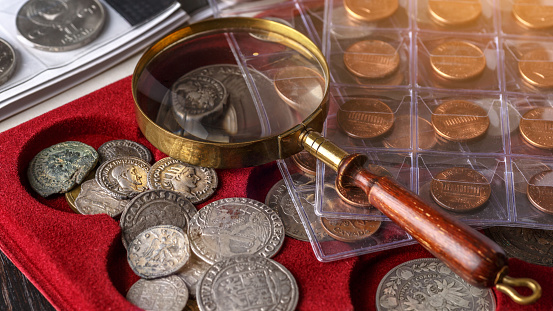Numismática. Antiguas monedas coleccionables hechas de plata sobre una mesa de madera. Monedas en el álbum. Colección de monedas antiguas. Lupa photo