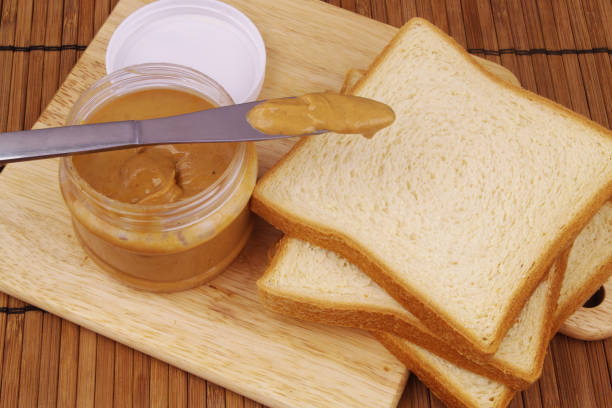 istock Peanut butter spread with bread slices and table knife 1369296429