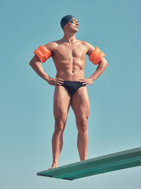 scatto a figura intera di un bel giovane atleta di sesso maschile in piedi su un trampolino all'esterno - arm band foto e immagini stock