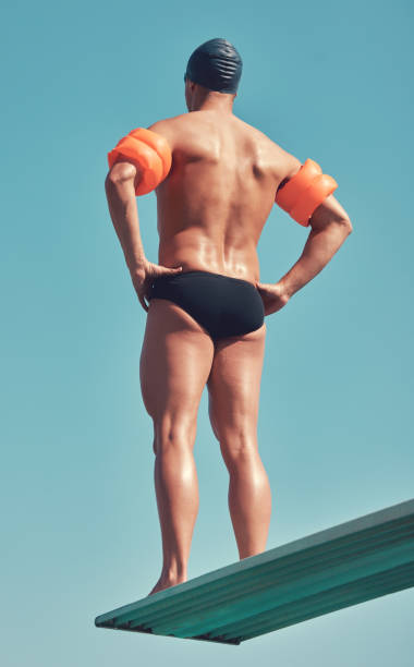 scatto di retrovisione di un atleta maschio irriconoscibile in piedi su un trampolino all'esterno - arm band foto e immagini stock