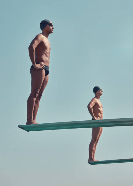 pełnometrażowe ujęcie dwóch przystojnych młodych sportowców stojących na deskach do nurkowania na zewnątrz - diving board zdjęcia i obrazy z banku zdjęć