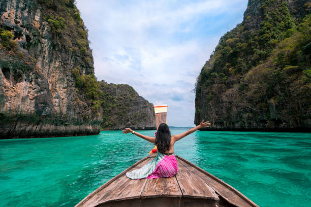 happy asian woman traveler sit on a long-tailed boat looking at beautiful natural pileh lagoon krabi in phi phi island. sea travel phuket thailand - phi phi islands imagens e fotografias de stock