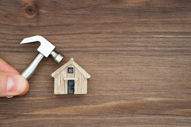 istock Holding a miniature hammer close to a tiny house 1369299148